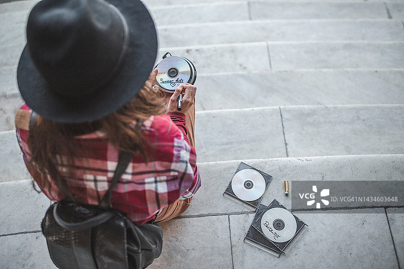 一位年轻女子用记号笔在光盘上写名字的背影图片素材