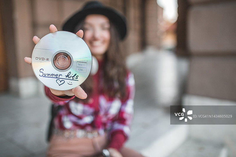 年轻微笑的女人拿着夏季热门歌曲CD的特写图片素材