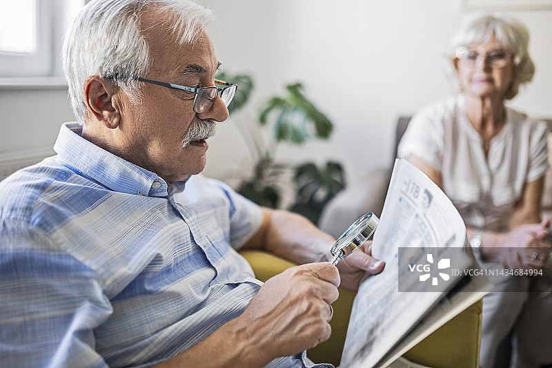 老年男人拿着放大镜辅助阅读图片素材