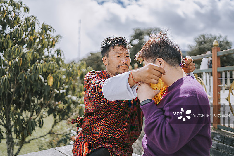 不丹男子展示中国女游客制作万寿菊花环图片素材