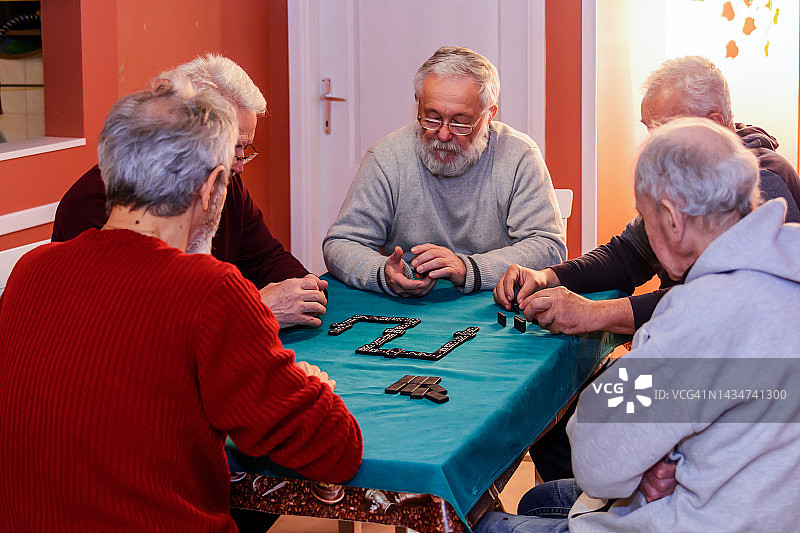 一群老年人在公寓里玩多米诺骨牌，其乐融融图片素材