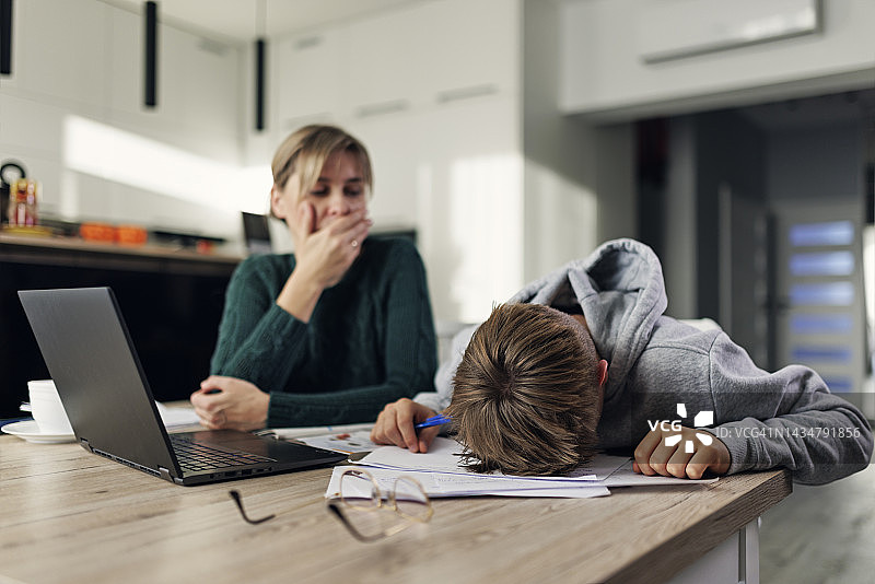 沮丧的母亲帮助沮丧的儿子完成非常困难的家庭作业图片素材