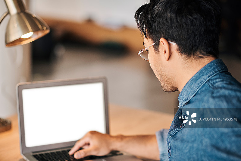 男人在夜晚的灯光下工作，肩上搭着笔记本电脑，进行SEO、营销或广告图片素材