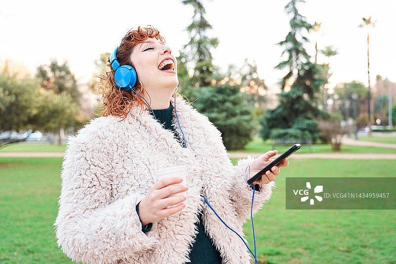 戴着耳机用手机的开怀大笑的女人特写图片素材