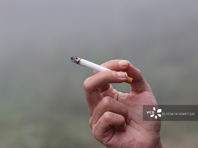 手持燃烧香烟的特写图片素材