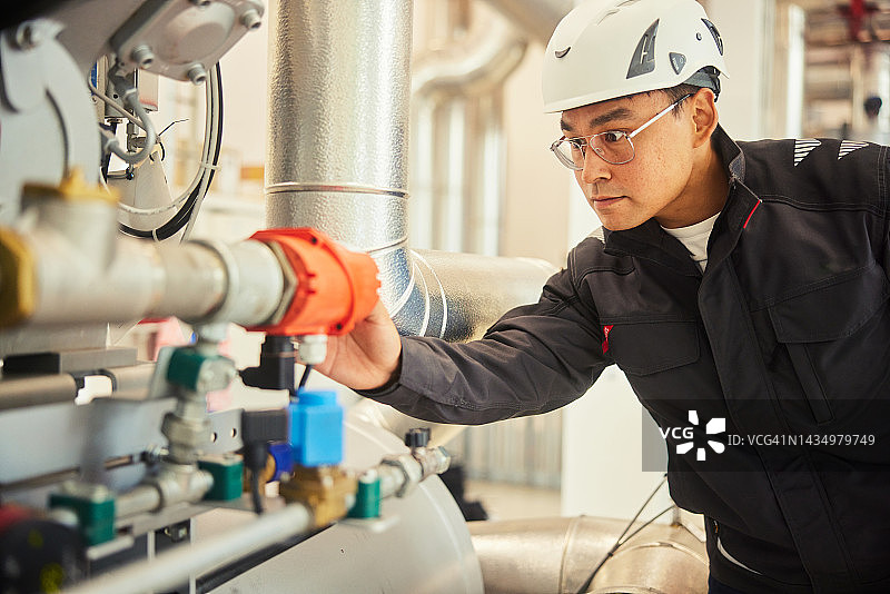 年轻工程师在发电站工作时检查仪表图片素材