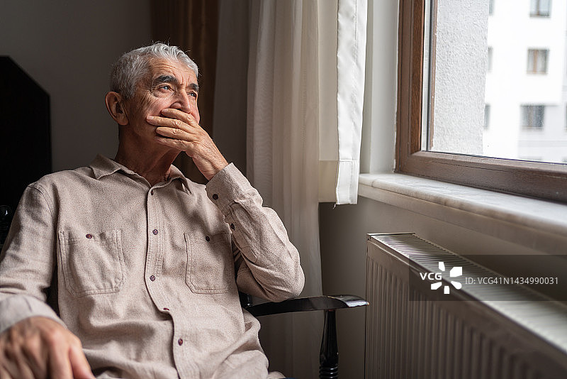 透过窗户沉思的老年男人图片素材