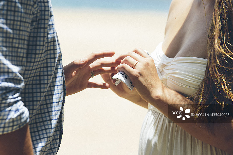 在夏威夷考艾岛海滩婚礼上新娘为新郎戴戒指图片素材