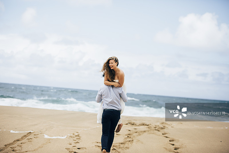 新郎新娘在沙滩上奔向大海。夏威夷考艾岛海滩婚礼图片素材