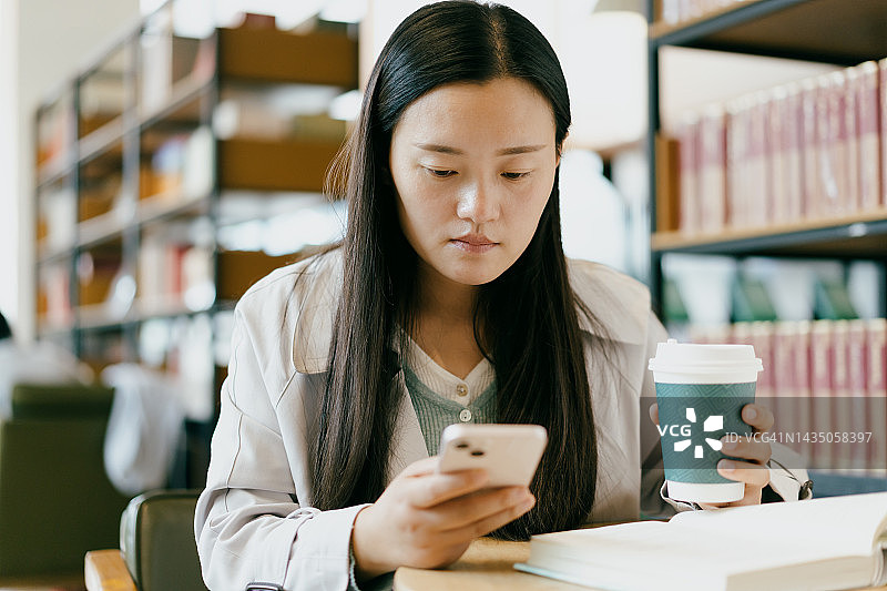 亚洲女孩在图书馆使用智能手机图片素材
