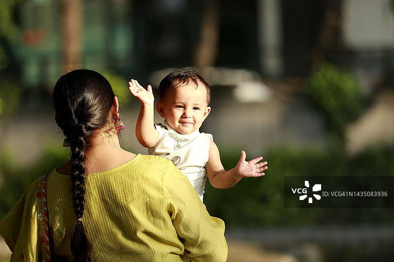 户外，母亲抱着孩子坐在腿上图片素材