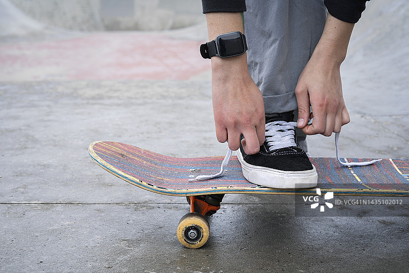 一个年轻女孩在滑板上系运动鞋带图片素材