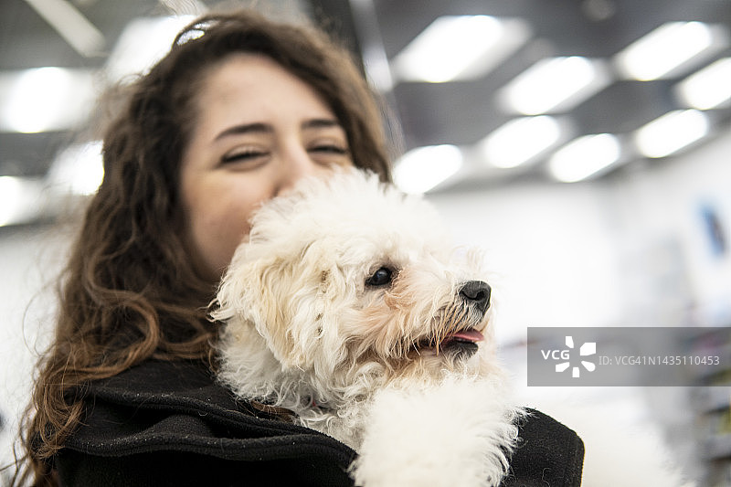在购物中心里抱着狗微笑的女孩图片素材