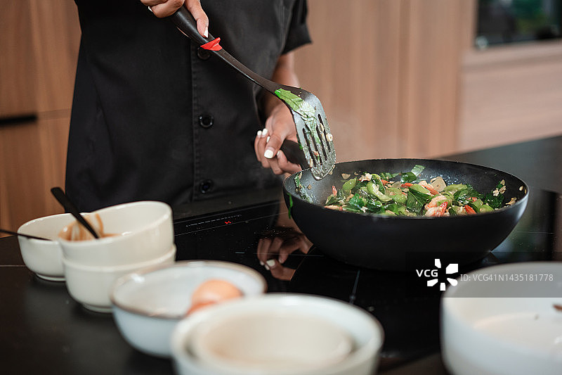 厨师在煎锅中翻炒蔬菜图片素材