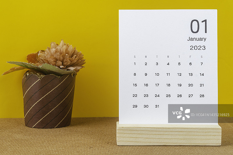 2023年桌面日历：一月，组织者计划和安排黄色纸背景上手工花的截止日期图片素材