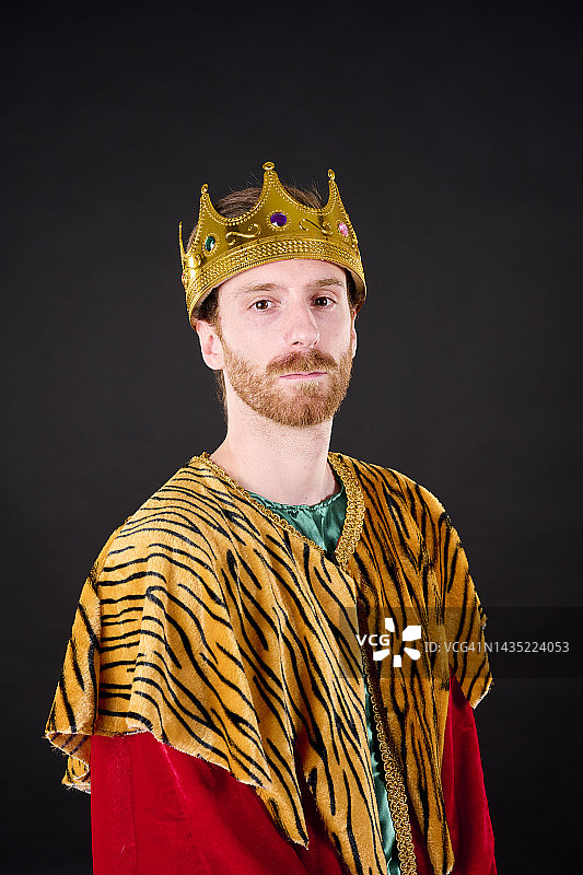 特写：红发络腮胡男子头戴皇冠，身穿红裙，看向镜头图片素材