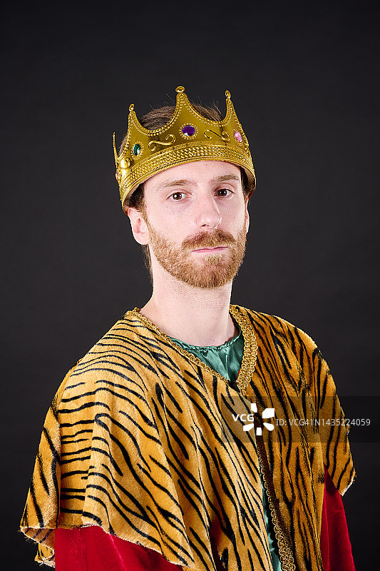 特写：红发络腮胡男子头戴皇冠，身穿红裙，看向镜头图片素材