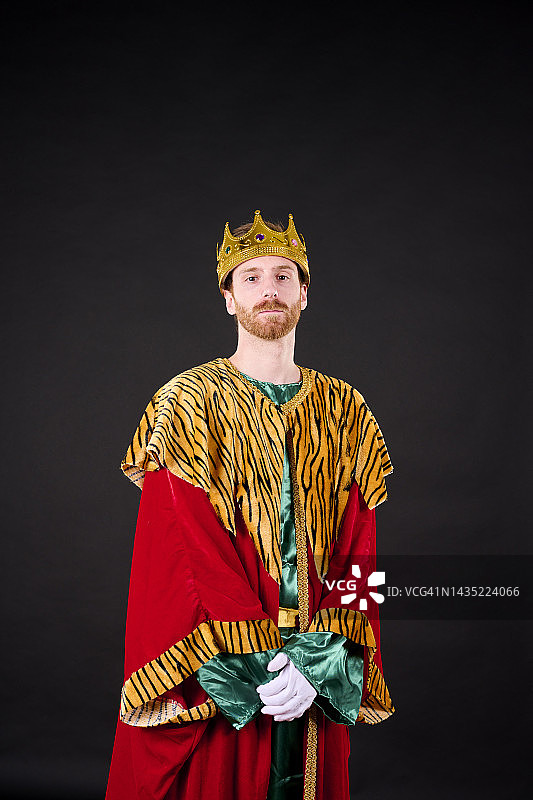 戴着王冠和国王服装的红发络腮胡年轻人看着镜头图片素材