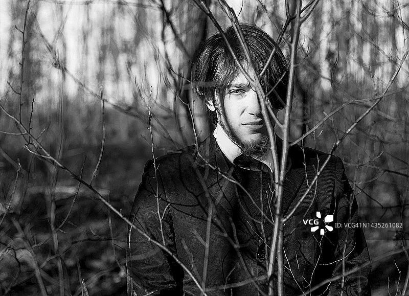 站在树林里看向镜头的年轻优雅男士肖像图片素材