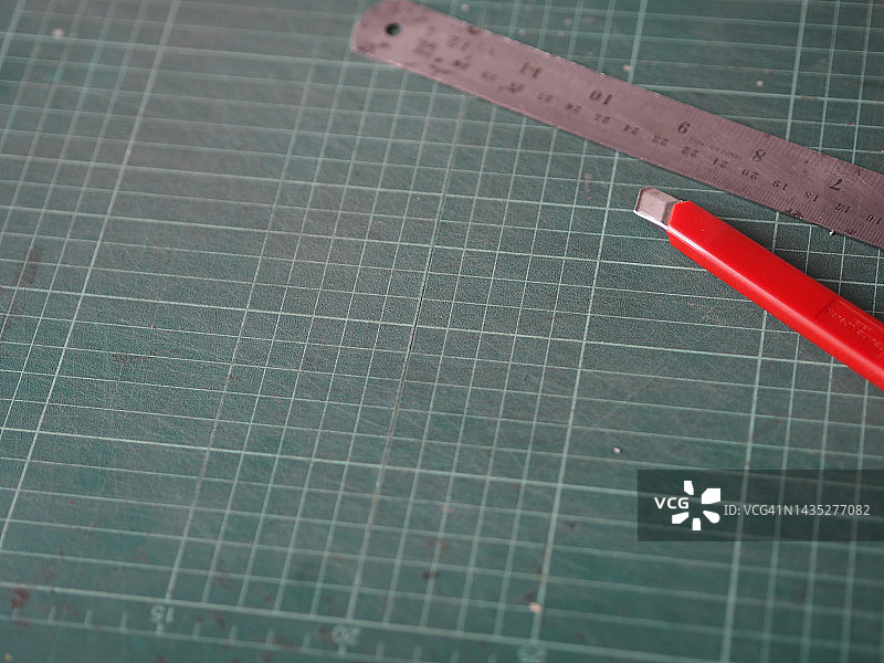 红色切割器和钢脚放置在切割垫上图片素材