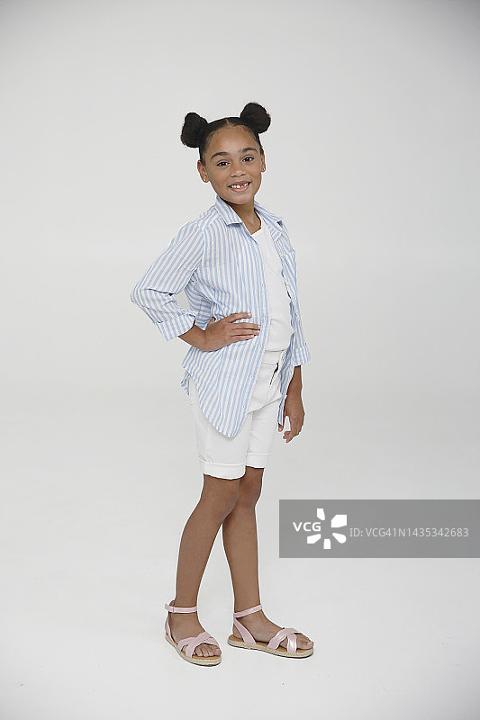 扎着两个发髻的年轻拉丁裔Z世代女孩在工作室里穿着休闲服装，快乐地微笑图片素材