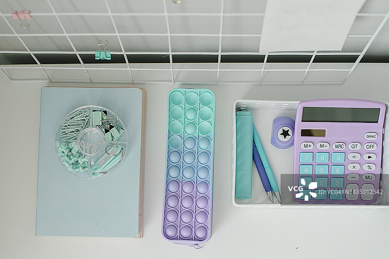 居家白色桌面、笔记本、计算器、铅笔盒、回形针、钢笔和马克笔在桌子上、返校季、自由职业者、家庭办公室图片素材