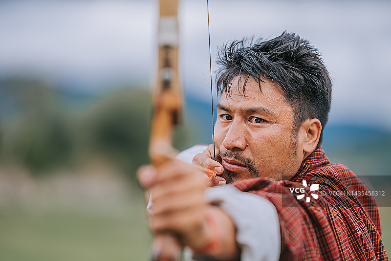 不丹男子在田野里练习射箭图片素材