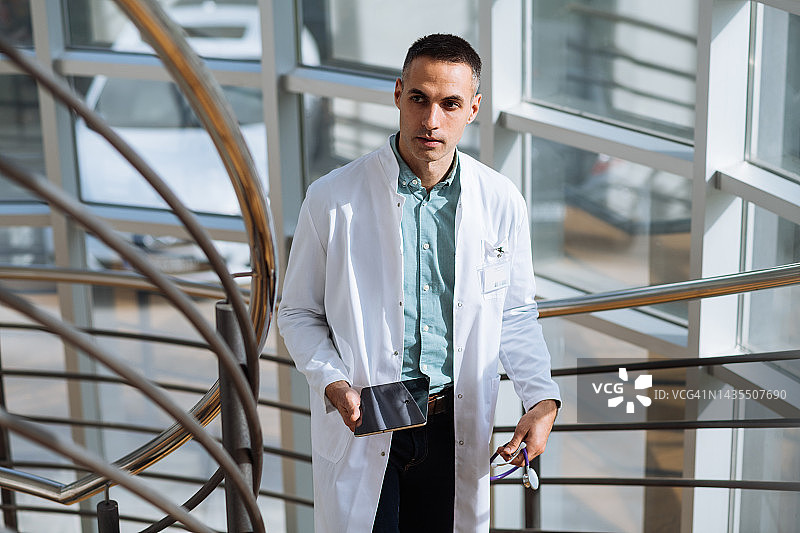 戴着听诊器、在医院使用平板电脑的男护士图片素材