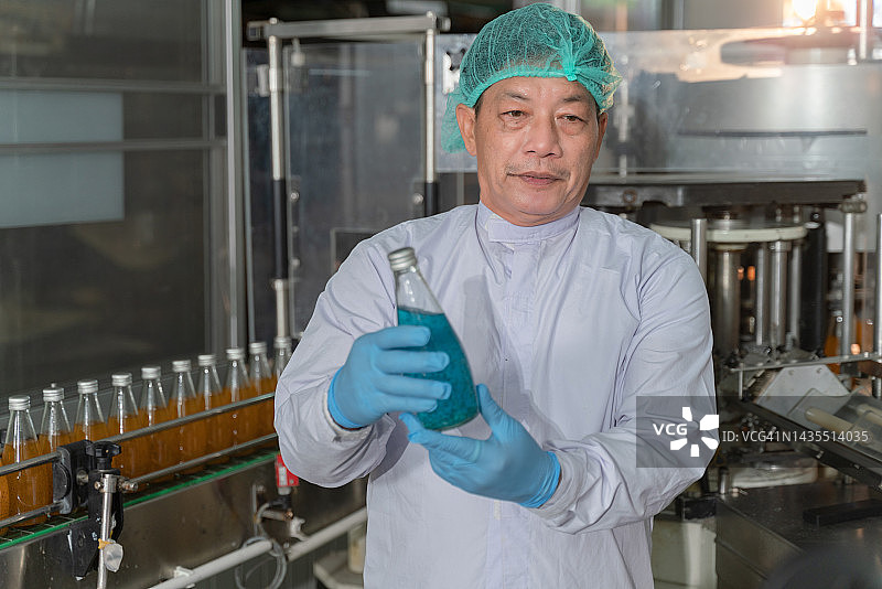 男工人在饮料厂检查罗勒籽饮料的质量图片素材