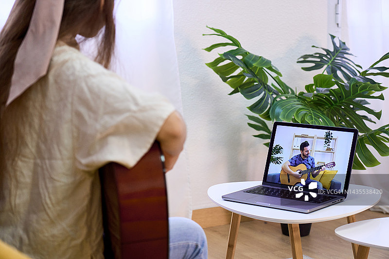 在家中通过笔记本电脑在线学习吉他的女士图片素材
