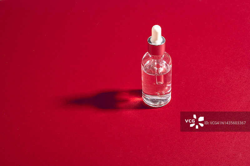 红色背景上的透明精华液瓶图片素材