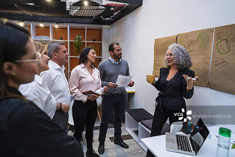 女人向同事们讲解公司上个月的财务数据图片素材