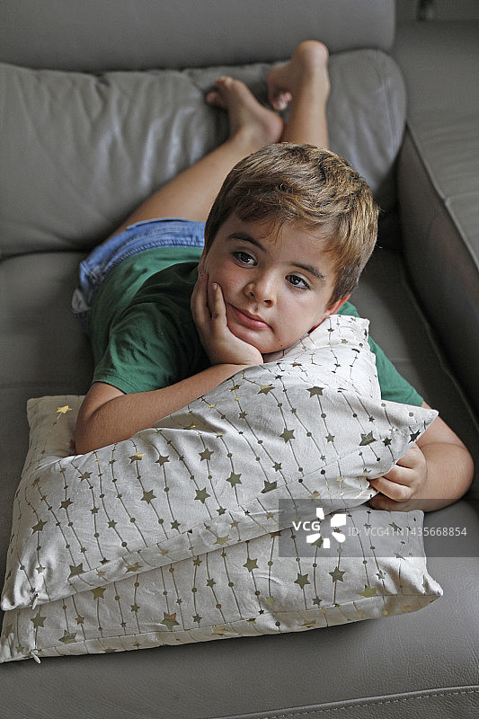 男孩躺在沙发上看电视的肖像图片素材