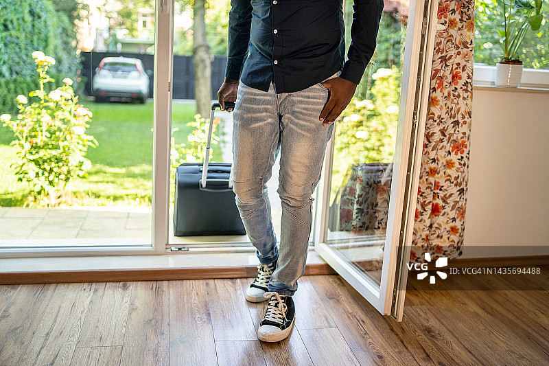 一位身份不明的男人带着行李箱回到家图片素材