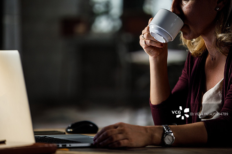 女人在家办公桌前工作，享受一杯咖啡图片素材