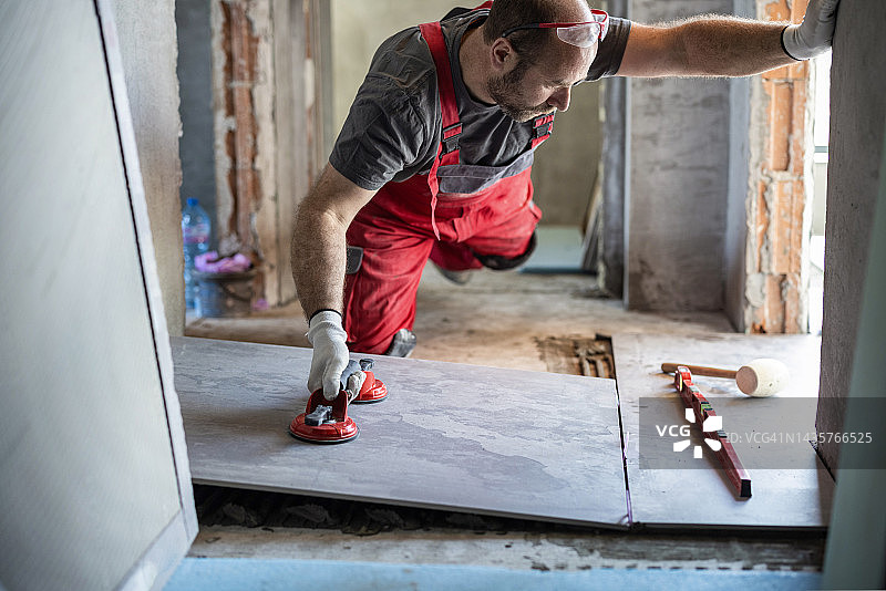 专业人员用真空手柄调整瓷砖图片素材