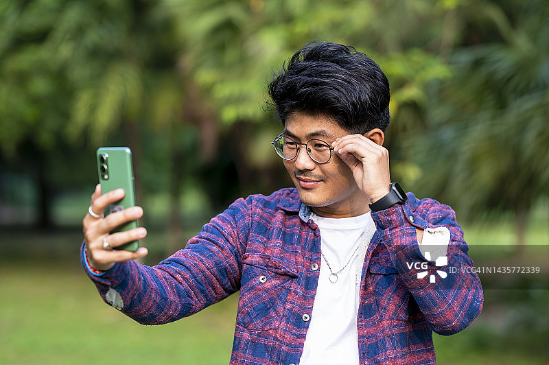 年轻男子在公园用智能手机自拍图片素材