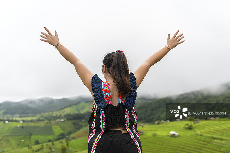 女游客在雾天张开双臂眺望美丽的青山图片素材