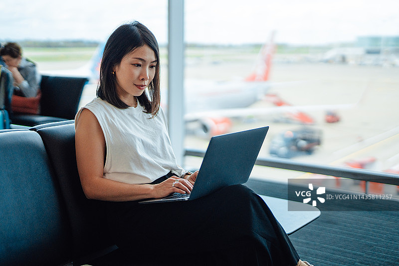 在机场候机时使用笔记本电脑的自信年轻女商人图片素材
