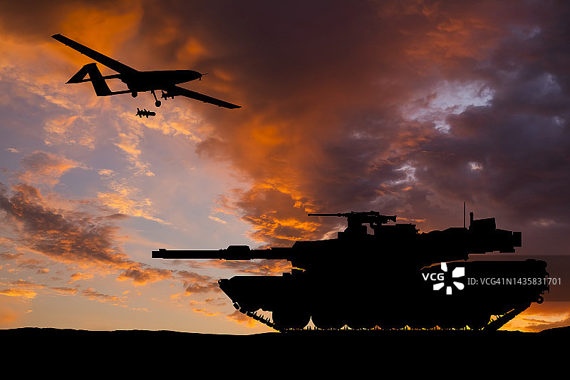 现代美式装甲坦克和日落背景下的战斗无人机图片素材