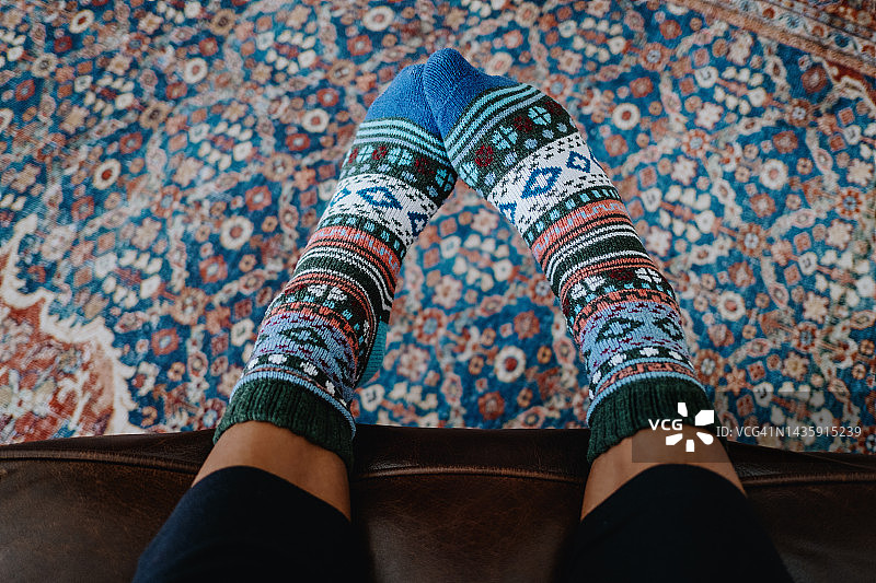 穿着彩色针织袜子的女人坐在矮座上图片素材