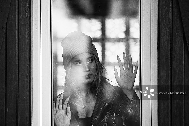 若有所思地透过窗户望去的悲伤孤独的年轻女人图片素材