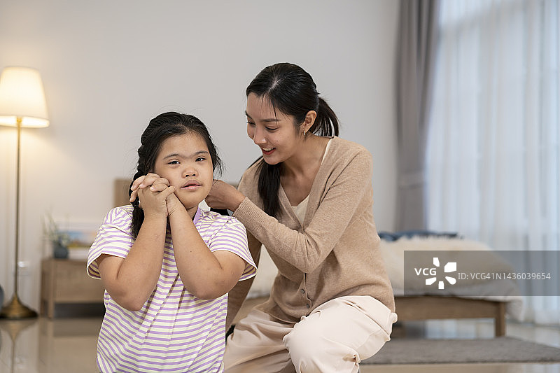 不同的姐妹互相做头发，其中一个女孩患有唐氏综合症图片素材
