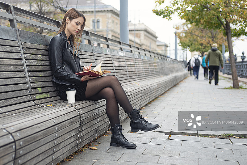 年轻女人在城市长椅上看书图片素材