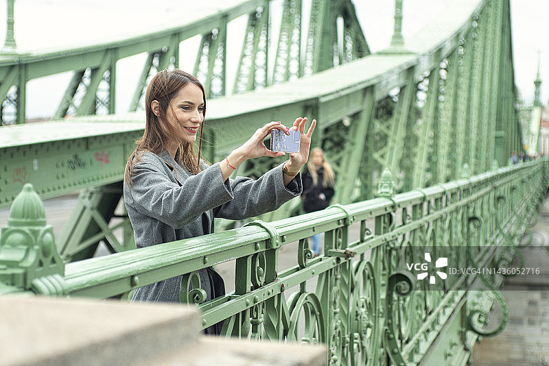 年轻女子用智能手机拍照图片素材