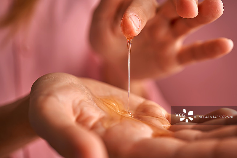 粉色装扮的女孩用手指触摸手掌中的凝胶化妆品图片素材