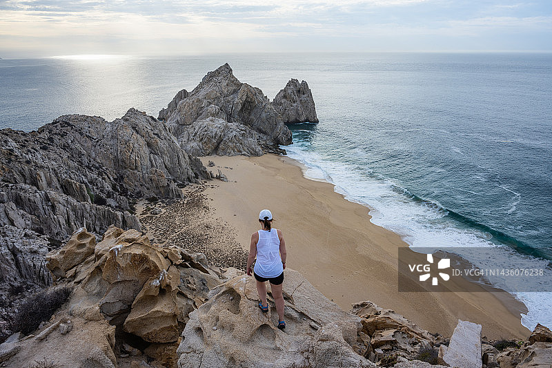 女子在日出时分，在沿海悬崖上放松图片素材