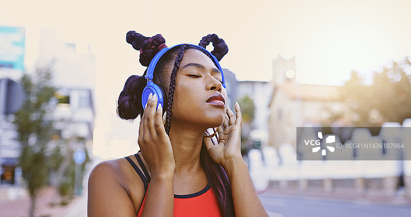 播客：快乐的黑人女性戴着耳机在城市里听广播和音乐图片素材