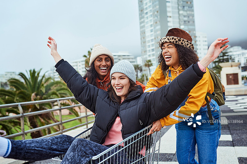 快乐、多元化的朋友们在冬天户外疯狂、滑稽和愚蠢的假期里互相推着手推车玩耍。微笑的女孩们一起在迈阿密享受手推车、欢笑、回忆和假期图片素材