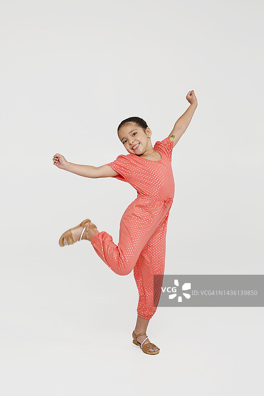 扎着马尾辫的年轻拉丁裔Z世代女孩肖像，在工作室环境中穿着休闲服装，举起双臂跳跃图片素材